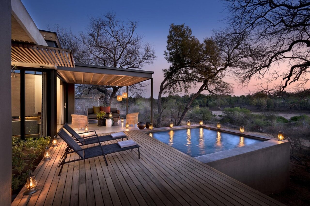 A private deck with a pool lit up in the evening light and surrounded by trees. This is a suite a Lion Sands Ivory Lodge, one of the best South African safari lodges.