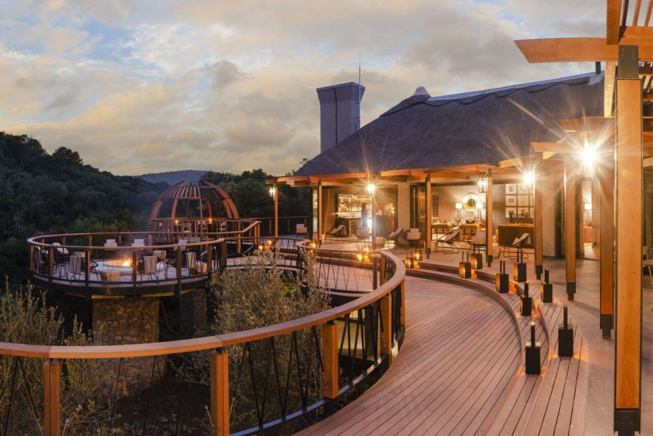 Eagles Crag decking in warm wood. The hut is lit up in the early evening, giving the impression of a cosy place to stay.
