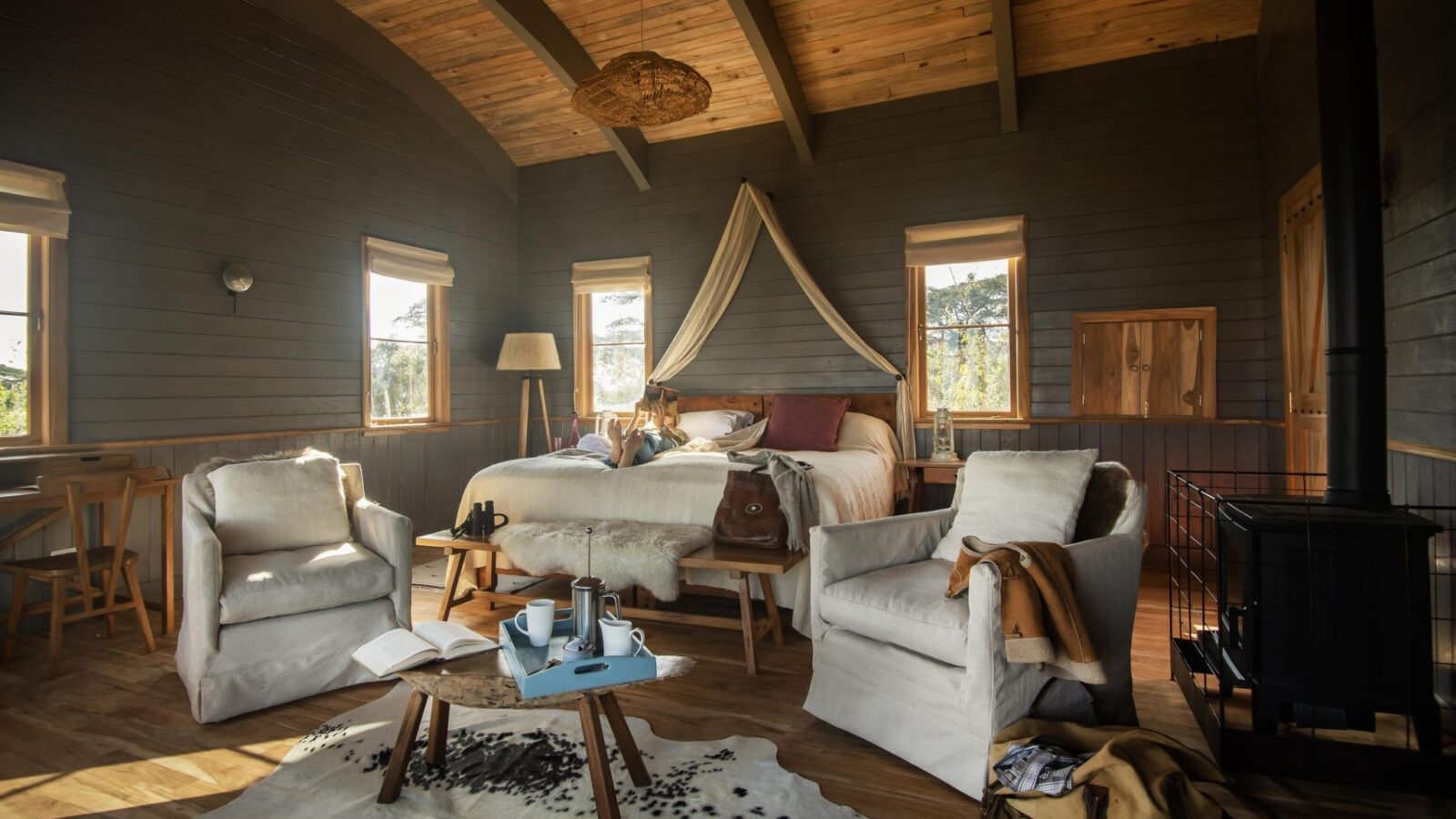 Inside Nomad-Entamanu-Ngorongoro. The room has dark green walls and wood pannelled ceilings The furnishings are cream and look like a cosy homely room.