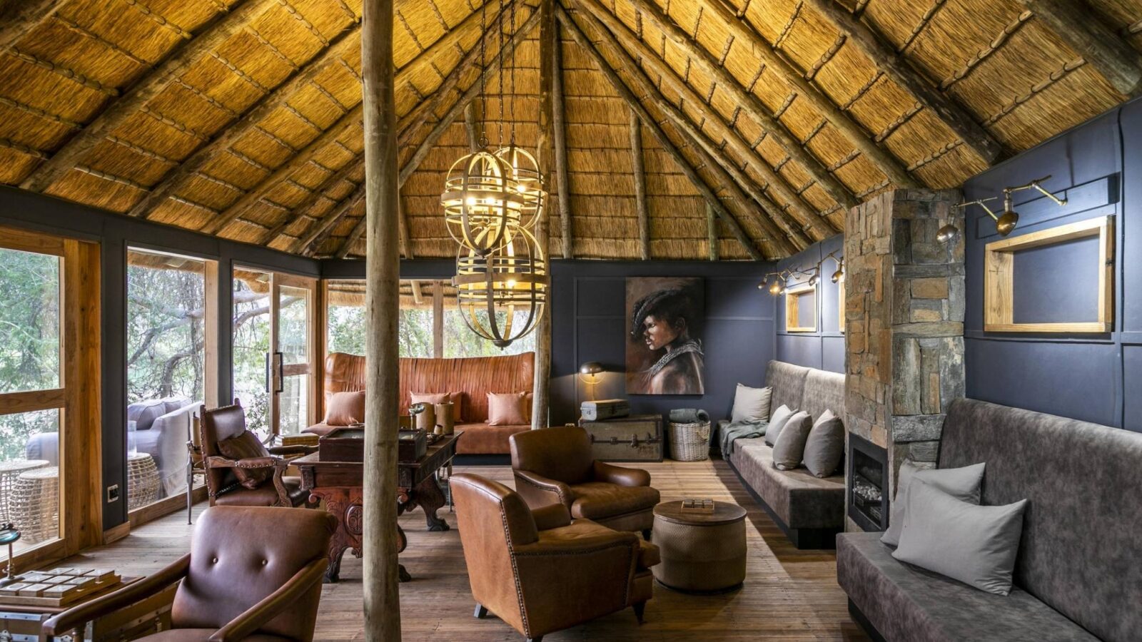 A high timber-roofed lodge with chairs and a photo of someone from the Himba tribe. Wilderness Serra Cafema in Namibia.